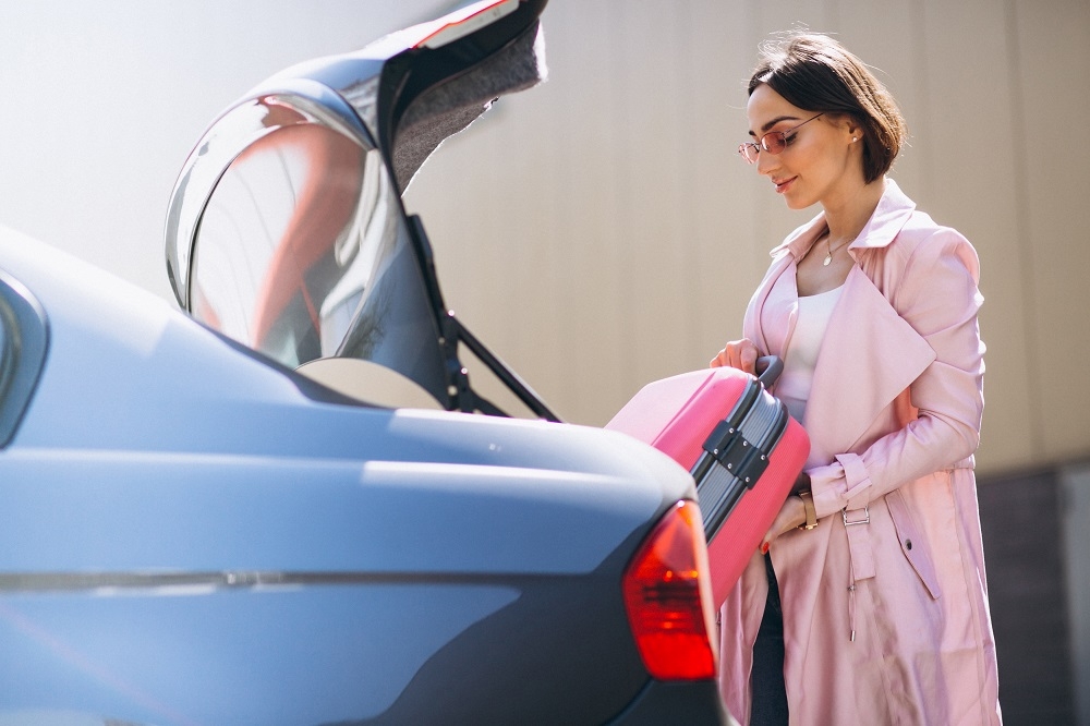 Femme qui charge le coffre de son véhicule avec une valise